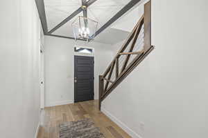 Foyer entrance with light wood-style flooring, stairway, and a chandelier