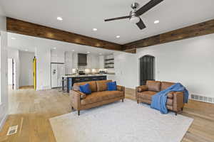 Living room with recessed lighting, beamed ceiling, light wood-type flooring, a ceiling fan, and arched walkways