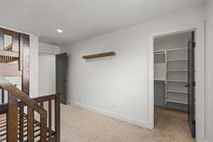 Unfurnished bedroom featuring light carpet, a walk in closet, and recessed lighting