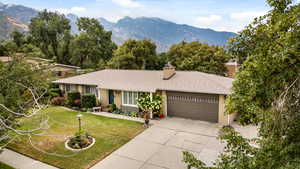 Single story home featuring roof with shingles, a chimney, a mountain view, driveway, and an attached garage
