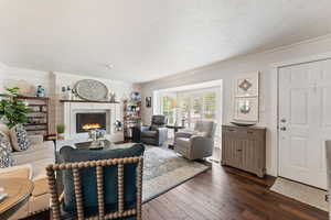 Living room with a premium fireplace, hardwood / wood-style floors, ornamental molding, a textured ceiling, and wood walls