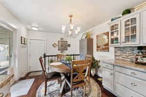 Dining space with dark wood-type flooring and a chandelier