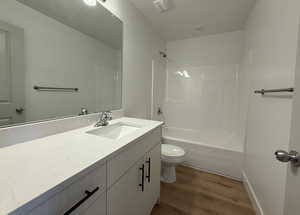 Full bathroom featuring washtub / shower combination, vanity, and dark wood-style floors
