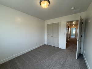 Unfurnished bedroom with dark carpet and a closet