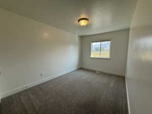 Empty room with carpet floors and a textured ceiling