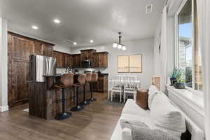 Kitchen with dark brown cabinetry, a kitchen island, recessed lighting, a breakfast bar area, and stainless steel appliances