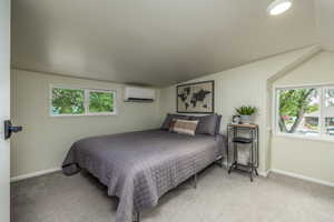 Carpeted bedroom featuring wooden walls, vaulted ceiling, and an AC wall unit