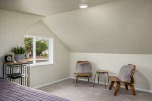 Bedroom featuring lofted ceiling, light carpet, and wood walls
