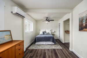 Bedroom with dark wood finished floors, a wall mounted air conditioner, and ceiling fan