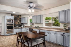 Kitchen featuring gray cabinetry, appliances with stainless steel finishes, ceiling fan, a warming drawer, and light tile patterned floors