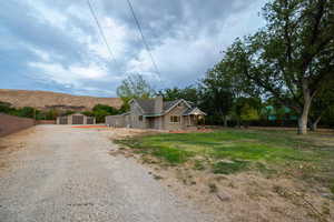 View of front of property featuring gravel driveway, an outdoor structure, and a chimney