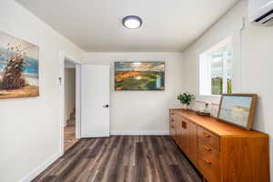 Corridor with a wall mounted air conditioner and dark wood-style flooring