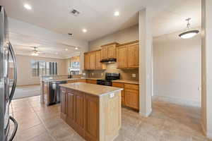 Kitchen featuring appliances with stainless steel finishes, a peninsula, recessed lighting, decorative backsplash, and a center island