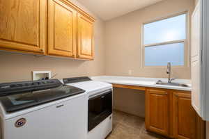 Laundry room featuring washing machine and dryer, cabinet space, and light tile patterned flooring