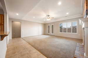 Unfurnished living room with a tray ceiling, light colored carpet, recessed lighting, light tile patterned flooring, and a ceiling fan