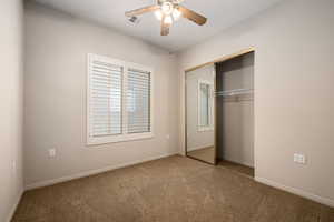 Unfurnished bedroom featuring carpet floors, a ceiling fan, and a closet
