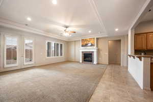 Unfurnished living room featuring a tray ceiling, recessed lighting, ceiling fan, a fireplace, and light carpet