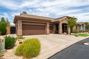 View of front of home with a gate, concrete driveway, stucco siding, and a tiled roof