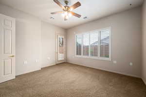 Carpeted spare room featuring baseboards and ceiling fan
