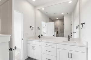 Full bathroom with a shower stall, double vanity, and recessed lighting