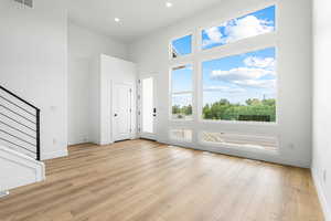 Foyer entrance with light wood finished floors, recessed lighting, and stairway