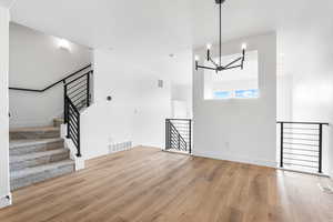 Unfurnished dining area with light wood finished floors, a chandelier, and stairway