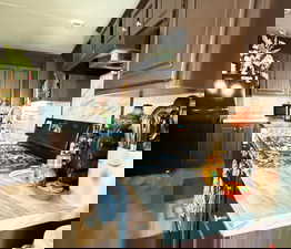 Kitchen with black appliances, light countertops, under cabinet range hood, tasteful backsplash, and light wood finished floors