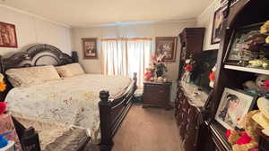 Bedroom featuring crown molding and dark colored carpet
