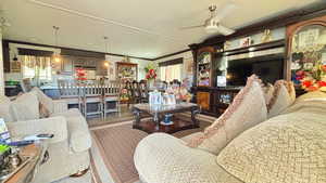 Living area featuring crown molding, wood finished floors, and ceiling fan