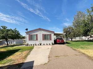 Manufactured / mobile home with a front lawn, a carport, and driveway