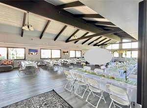 Dining space featuring a chandelier, beamed ceiling, wood finished floors, and high vaulted ceiling