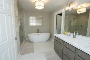 Bathroom featuring double vanity, a soaking tub, a marble finish shower, and light marble finish floors