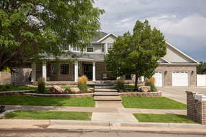 View of front of house featuring covered porch, concrete driveway, brick siding, and an attached garage