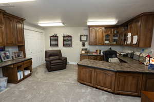 Kitchen with glass insert cabinets, a textured ceiling, dark brown cabinets, light carpet, and open floor plan