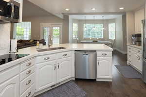 Kitchen featuring appliances with stainless steel finishes, open floor plan, light countertops, dark wood-type flooring, and recessed lighting