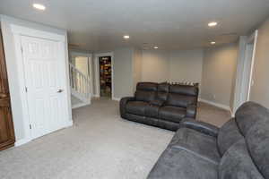 Living room with light carpet, recessed lighting, a textured ceiling, and stairway