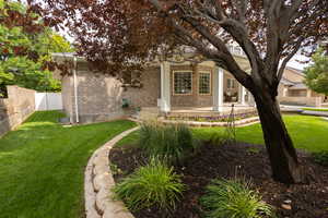 View of property hidden behind natural elements with brick siding and a patio