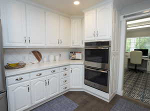 Kitchen featuring appliances with stainless steel finishes, white cabinets, light stone counters, dark wood finished floors, and recessed lighting