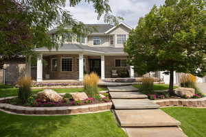 View of front facade with covered porch, a front lawn, and brick siding
