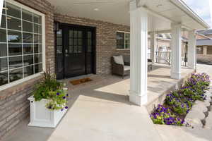Property entrance featuring covered porch and brick siding
