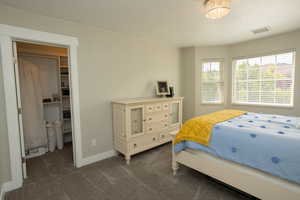 Bedroom with dark carpet and a walk in closet