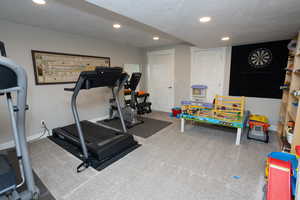 Exercise room featuring a textured ceiling, recessed lighting, and carpet