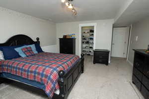 Bedroom featuring a textured ceiling, light carpet, and a spacious closet