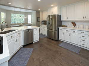 Kitchen with white cabinets, appliances with stainless steel finishes, recessed lighting, tasteful backsplash, and dark wood-style flooring