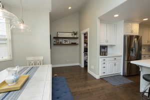 Kitchen with white cabinetry, stainless steel fridge, dark wood-type flooring, recessed lighting, and hanging light fixtures