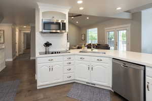 Kitchen featuring stainless steel appliances, white cabinetry, open floor plan, recessed lighting, and dark wood-type flooring