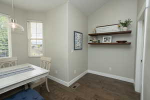 Dining space with healthy amount of natural light, dark wood-style flooring, and lofted ceiling