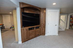 Living area featuring light carpet, recessed lighting, stairs, and a textured ceiling