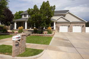 View of front facade featuring driveway, an attached garage, covered porch, and brick siding