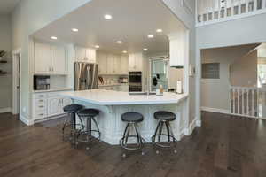 Kitchen featuring white cabinets, recessed lighting, a kitchen bar, a peninsula, and appliances with stainless steel finishes